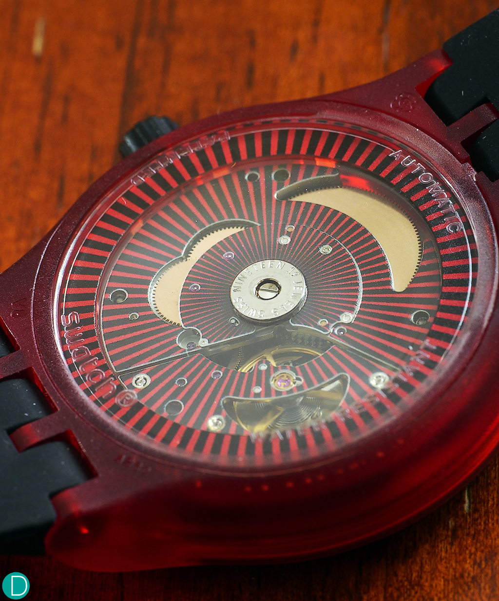 Swatch Sistem 51, red, caseback, showing the red markings on the movement bridge, visible through the transparent rotor.