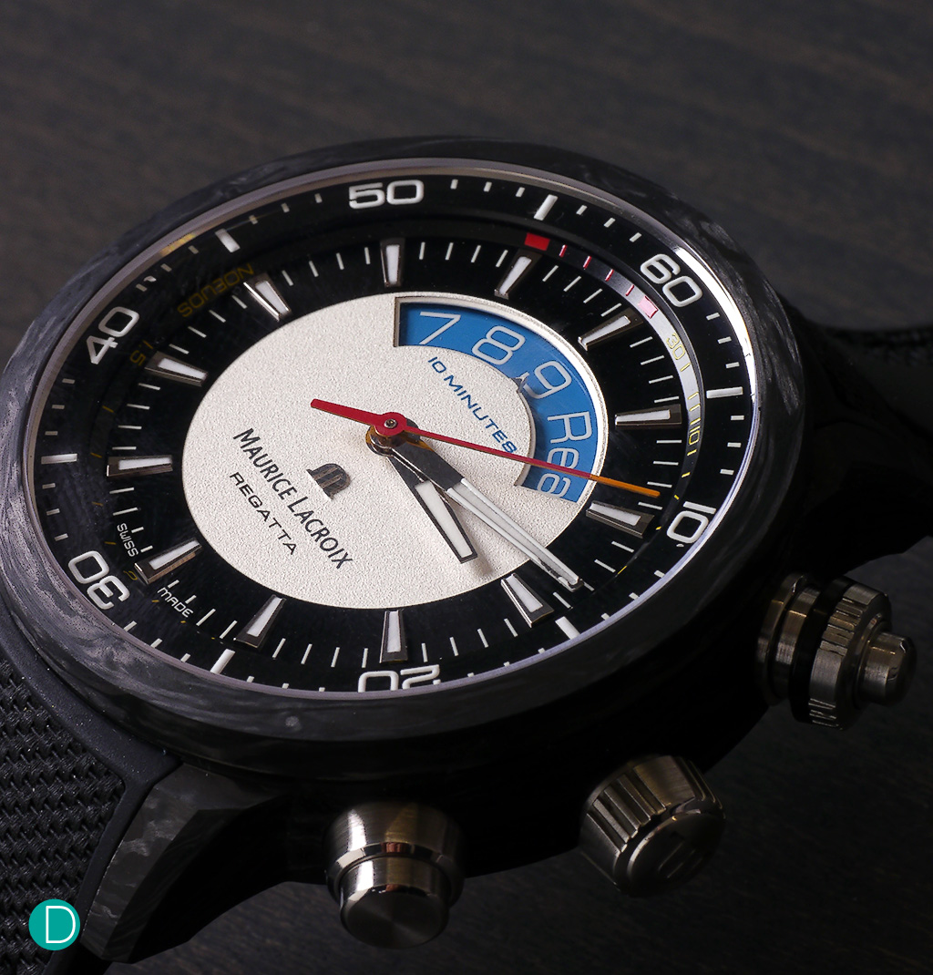 The Maurice Lacroix Pontos S Regatta dial. The dial is a study in contrasts and use of colours. Red and black are used for the yachting specific countdown disc visible through the aperture. The chapter ring for the hours and minutes are in jet black, offset by applique markers. A red seconds hand, tipped in orange and the minute hand tipped in white complete the picture.