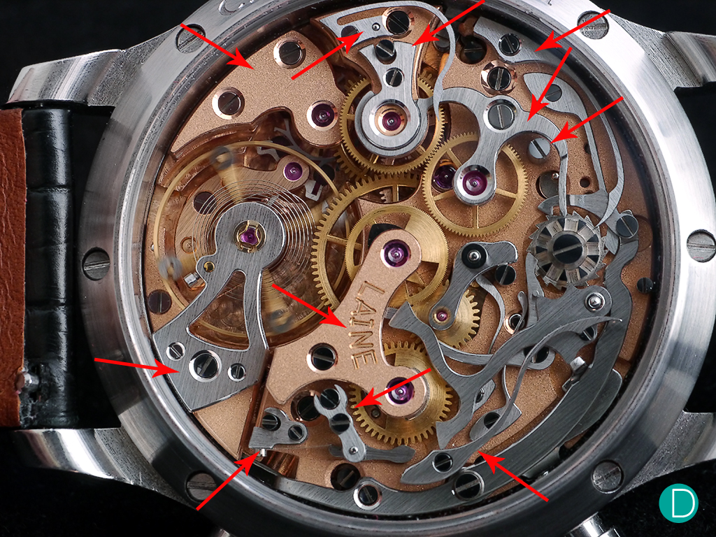 The Torsti Laine Chronograph is home to several in-house modifications: 4 brass bridges (one under steel balance bridge) specifically: 1 steel balance bridge, 3 springs, 2 chronograph clutch parts (top and under), clutch holder part, 3 eccentric posts and in minute counter area 7 other parts (including 2 eccentric screws). There are other new in-house components which are not visible in our image.