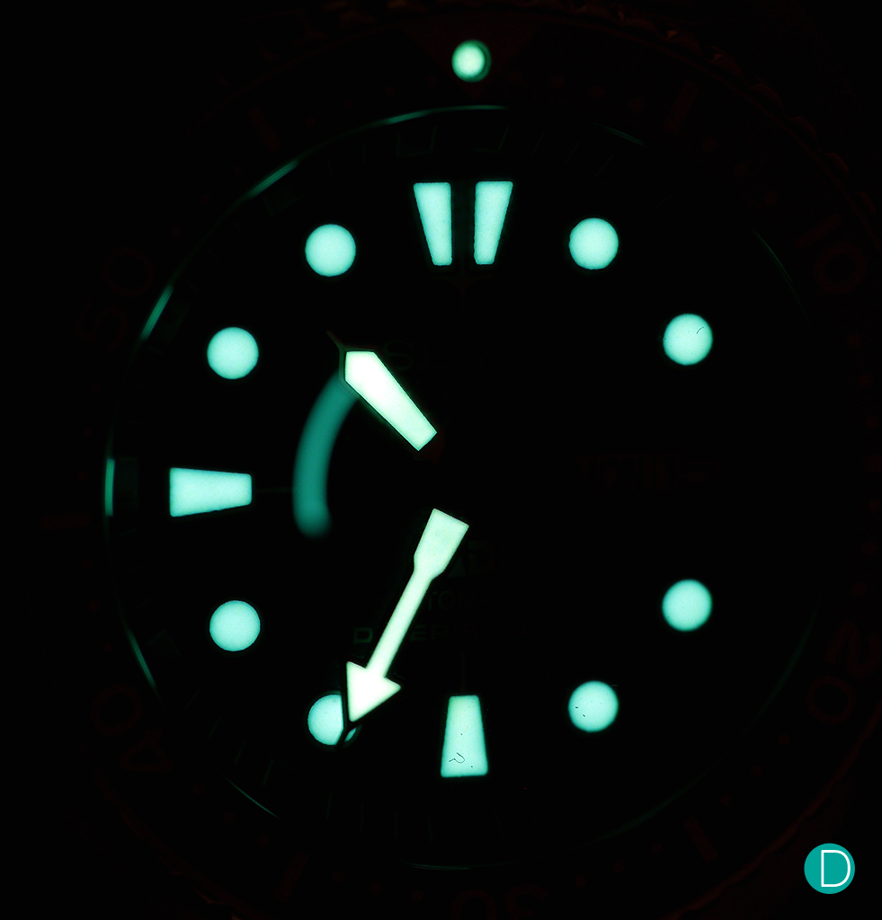 The very bright lume of the Seiko PADI Automatic Diver. Note the bright dot on top of the triangle is the center marker for the rotating bezel. At 3 o'clock, the luminous marker is absent as the space is taken by an aperture showing the day and date.