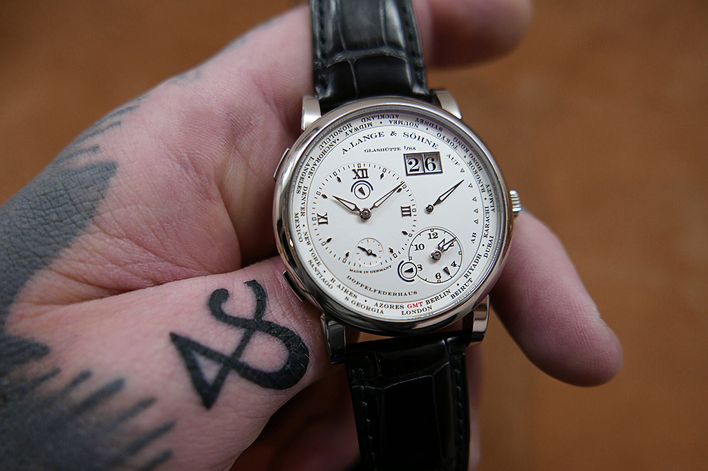 The Lange 1 Timezone. Note the tattoo of the Ampersand on Benjamin's thumb which is the same font as the one used by Lange.