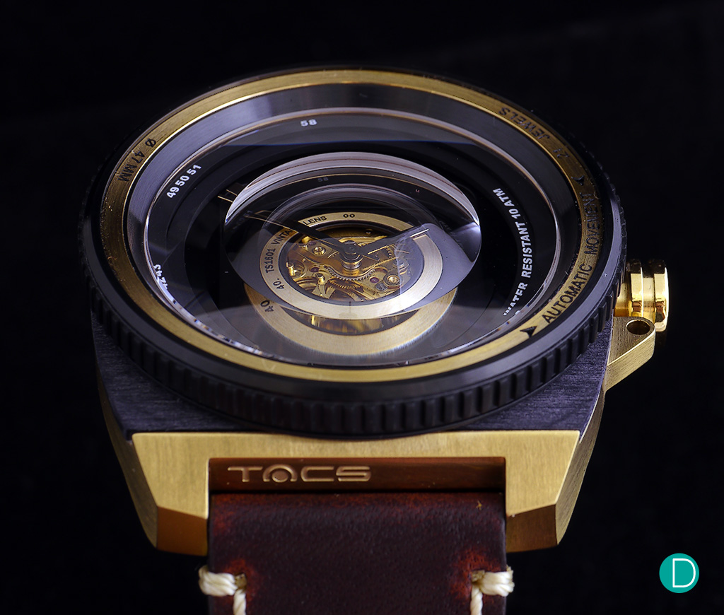 The case is in 316L stainless steel with black PVD and gold plating. The bezel is also in stainless steel with black pvd and designed to look like the focusing ring of a lens. Note also the markings on the inside of the bezel mimics the markings on a traditional lens.
