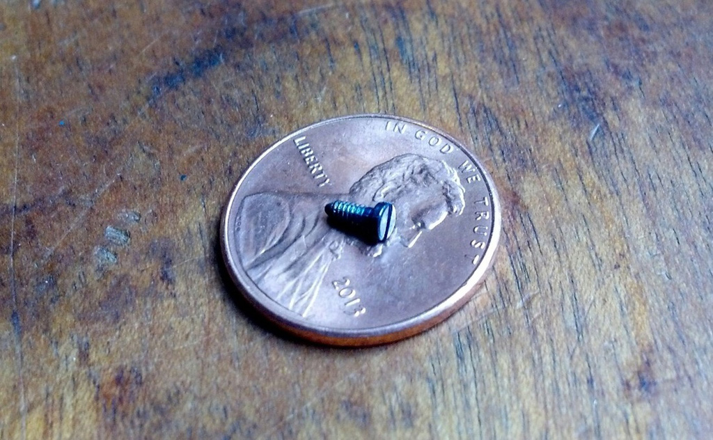 A typical blued screw. The screw slot is less than 1mm high, too much tension and the flathead slips out and causes a micro scratch on the surface. Heat-treated blued screws are only blue to a couple of microns thickness, a scratch would become obvious fairly quickly.